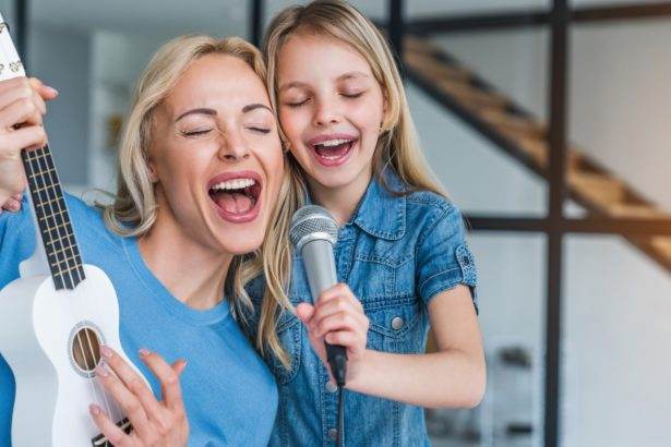 Caucasian mother with little girl singing in karaoke at home