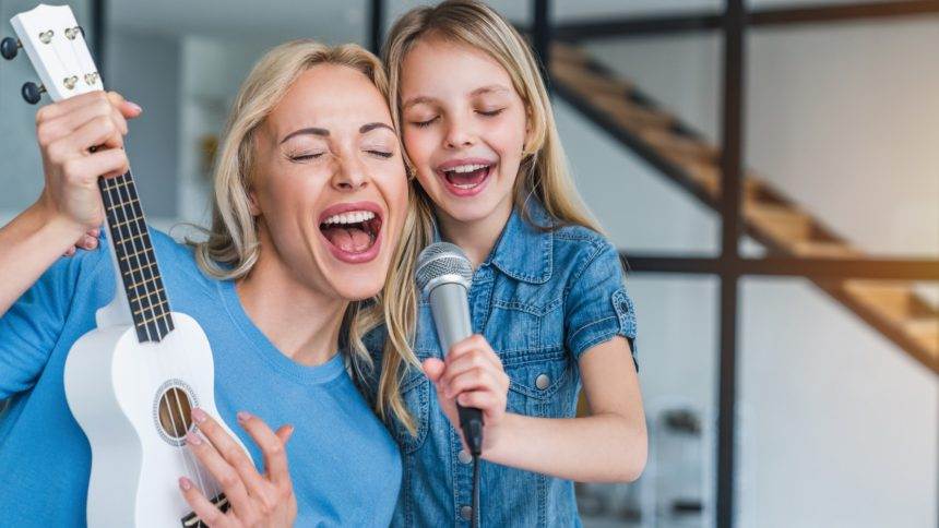 Caucasian mother with little girl singing in karaoke at home
