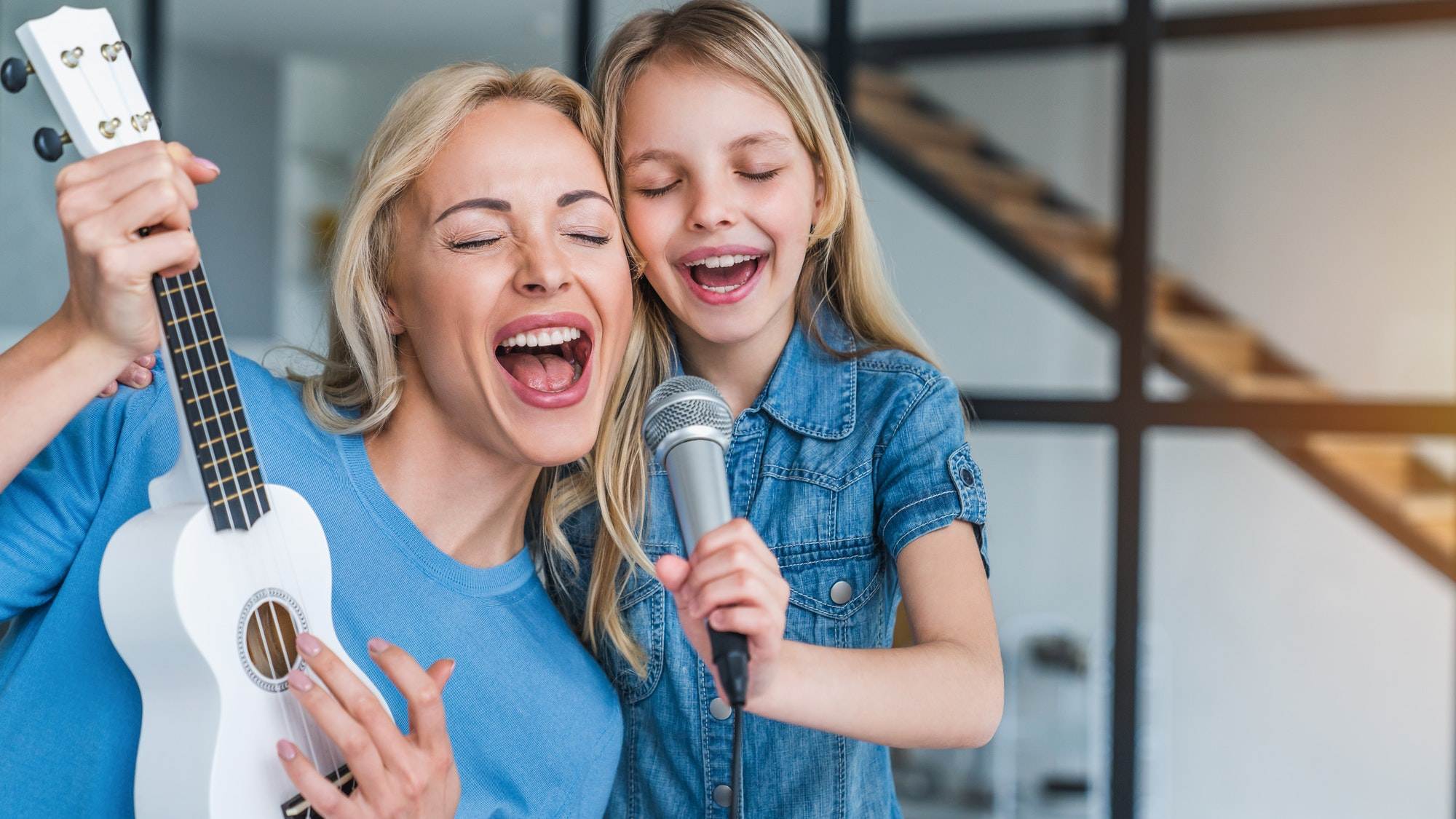 Caucasian mother with little girl singing in karaoke at home