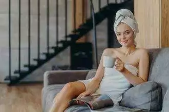 Photo of adorable young woman has makeup and healthy skin, holds mug of coffee